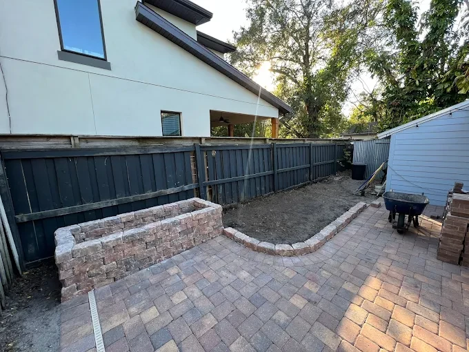 Backyard paver patio with a matching paver seat wall and raised planter