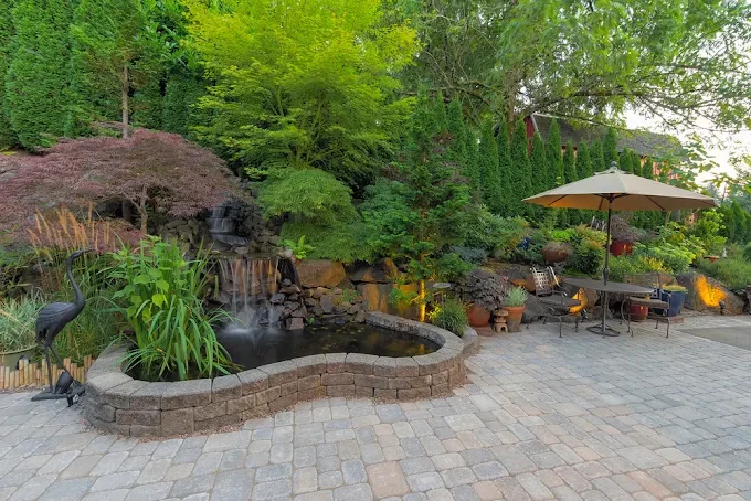Paver patio beside a landscaped pond and waterfall
